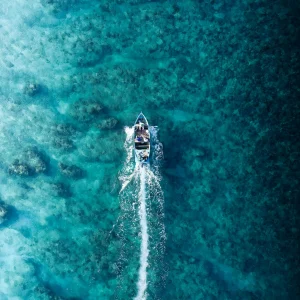Aerial view of a speedboat cutting a wake across blue ocean