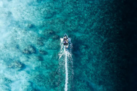 Aerial view of a speedboat cutting a wake across blue ocean
