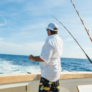 Angler standing on a sportfishing boat beside a rack of trolling rods