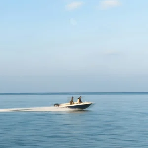 Three guests riding a motorboat under bright cloud cover