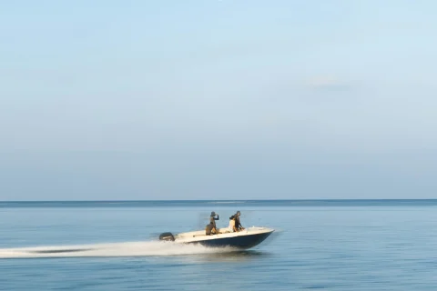 Three guests riding a motorboat under bright cloud cover