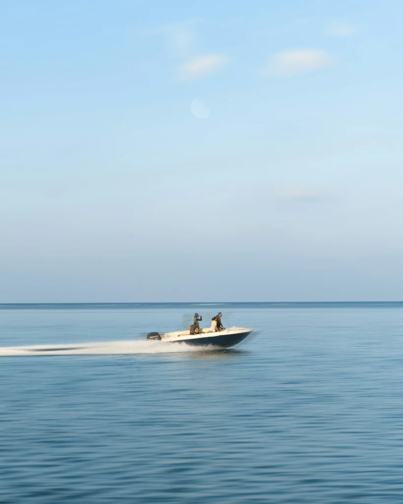 Three guests riding a motorboat under bright cloud cover